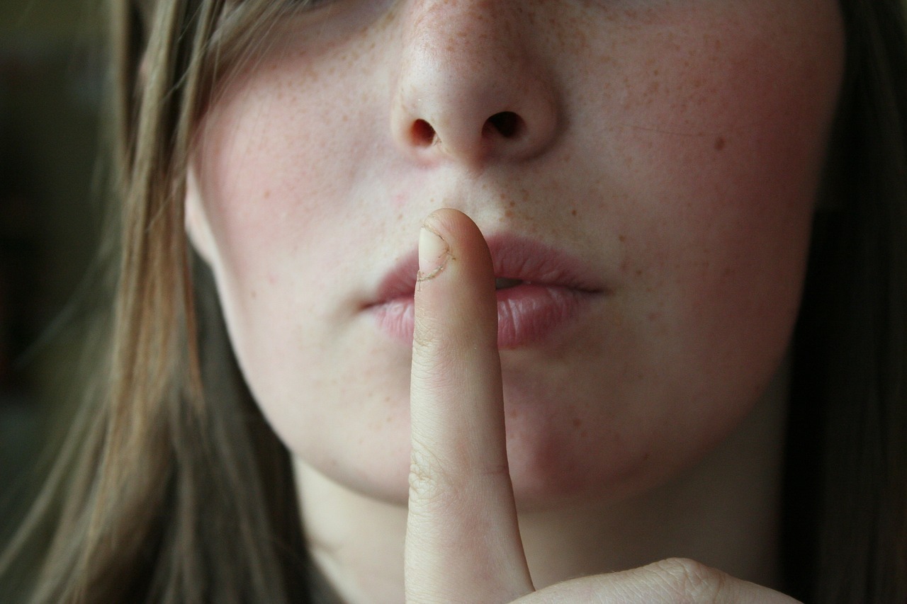Frau legt Finger auf die Lippen