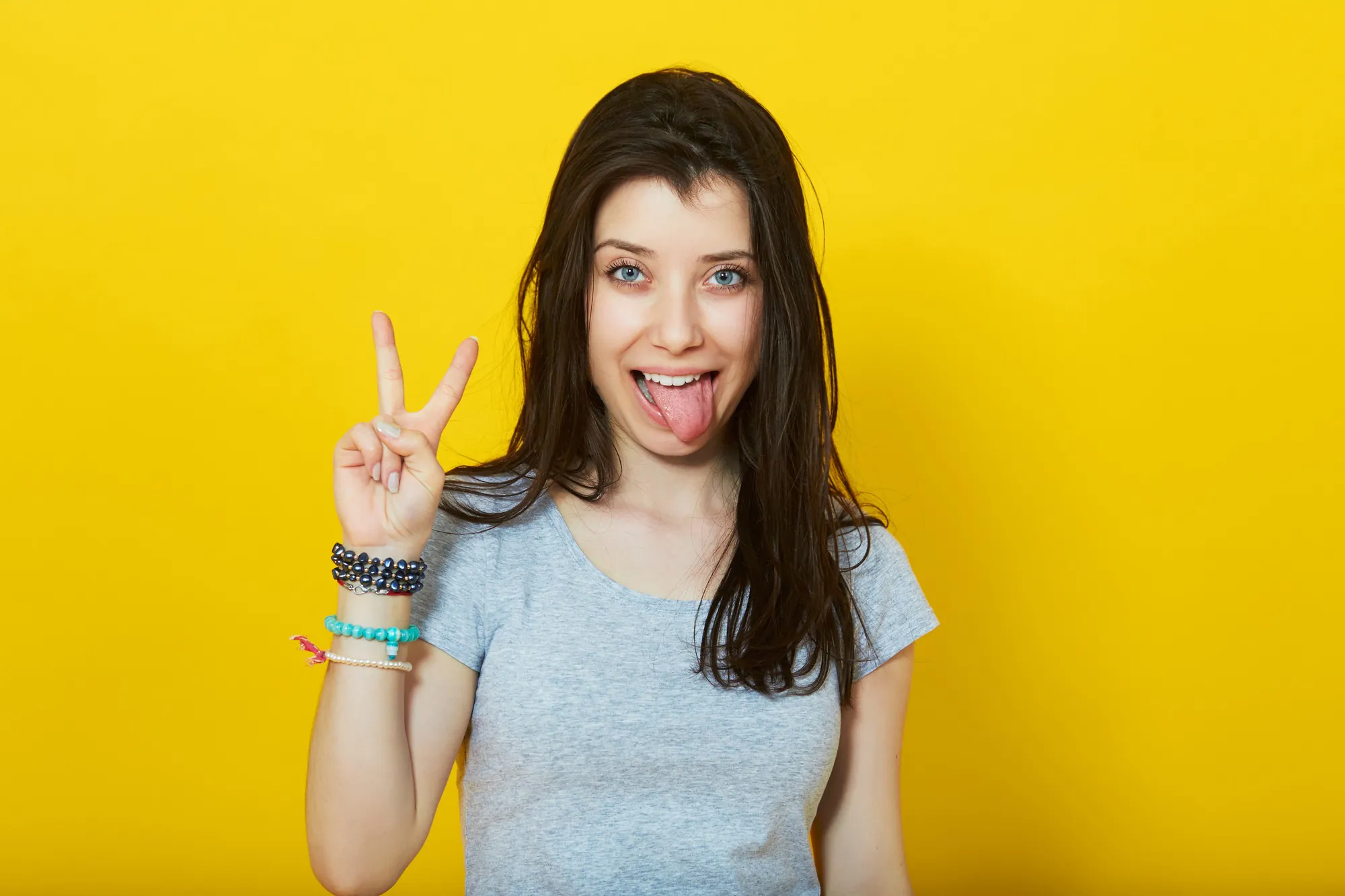 junge Frau macht Victoryzeichen mit herausgestreckter Zunge